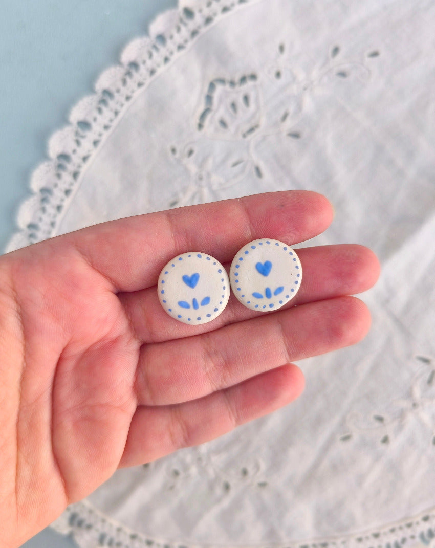 White porcelain earrings with blue tulip design with a tiny heart in the place of the bloom.