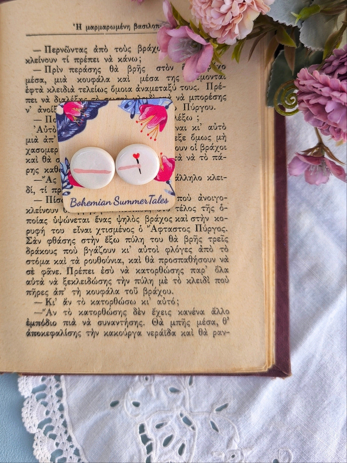 A pair of porcelain stud earrings forming together a hand offering a flower in a shape of a heart